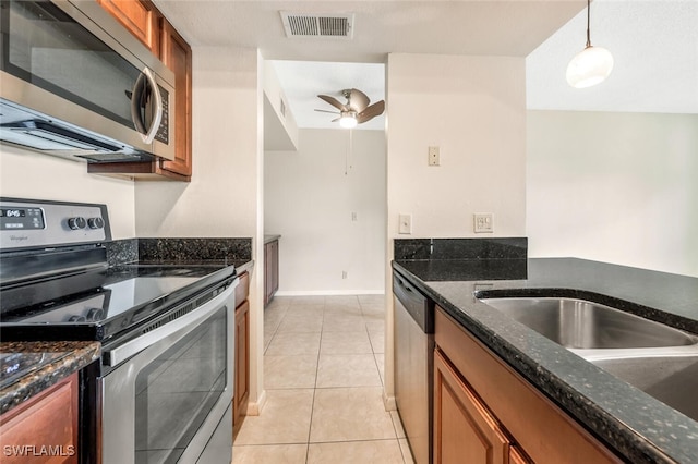 kitchen featuring dark stone counters, stainless steel appliances, ceiling fan, pendant lighting, and light tile patterned flooring