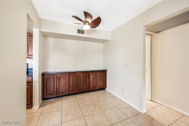 tiled spare room with ceiling fan and a textured ceiling