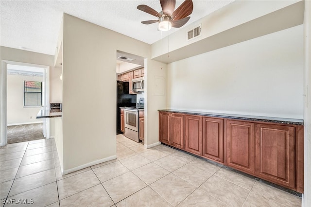 kitchen with ceiling fan, light tile patterned floors, stainless steel appliances, and a textured ceiling