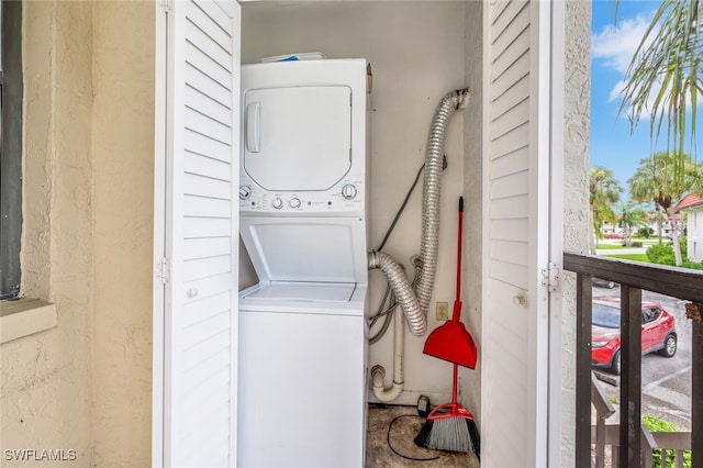 clothes washing area with stacked washing maching and dryer