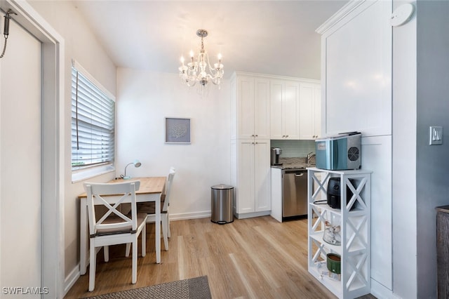 kitchen with backsplash, stainless steel dishwasher, pendant lighting, a notable chandelier, and white cabinetry