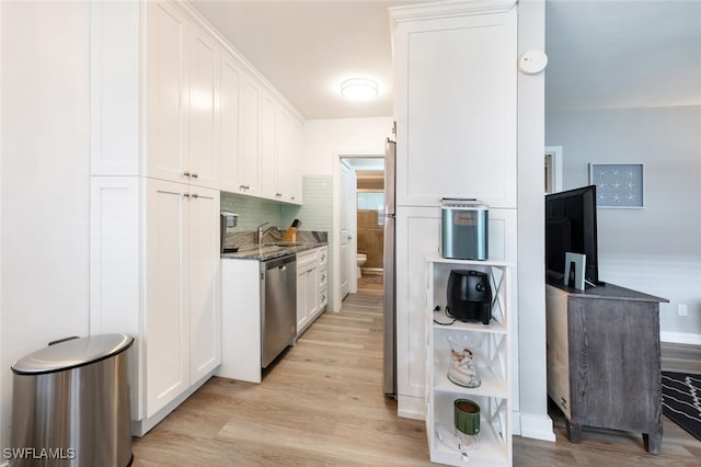 kitchen featuring decorative backsplash, light hardwood / wood-style flooring, dark stone countertops, dishwasher, and white cabinetry