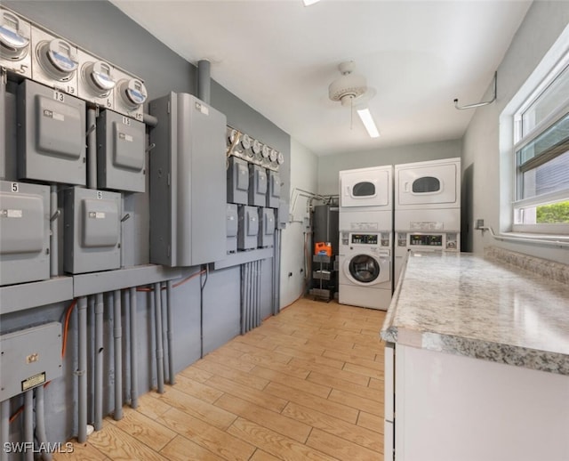 kitchen with gas water heater, light hardwood / wood-style flooring, electric panel, stacked washer and dryer, and white cabinets