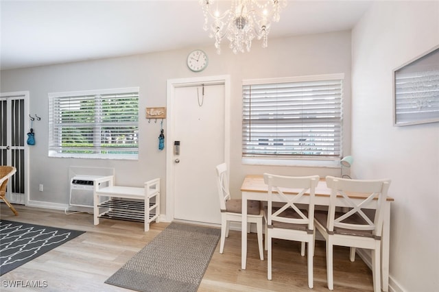 dining area featuring a notable chandelier, light hardwood / wood-style flooring, and a wall mounted AC