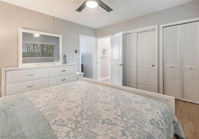 bedroom featuring hardwood / wood-style flooring, ceiling fan, and multiple closets