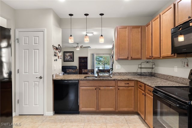 kitchen featuring light stone counters, ceiling fan, sink, black appliances, and decorative light fixtures