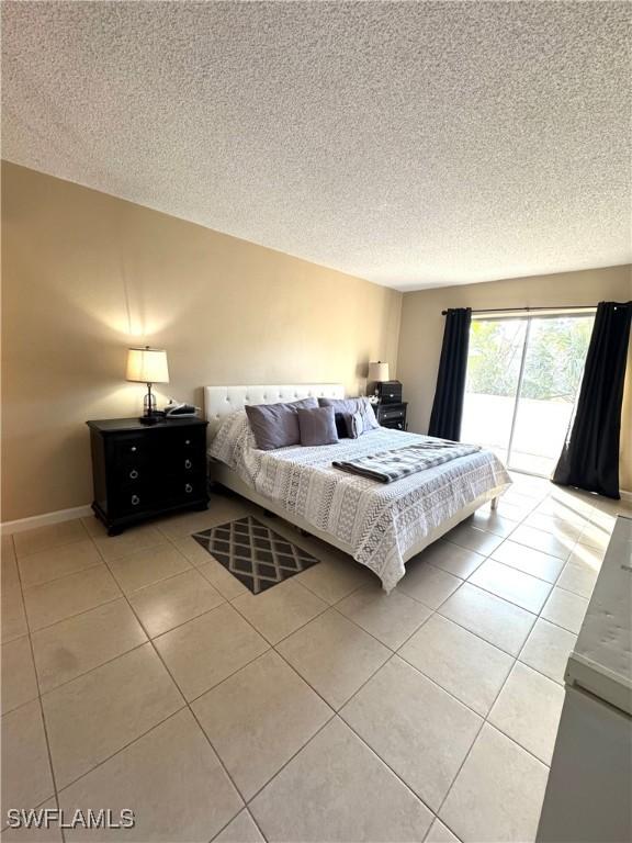 tiled bedroom featuring access to exterior and a textured ceiling