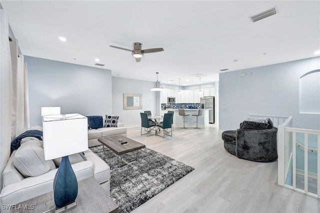 living room with ceiling fan and light wood-type flooring