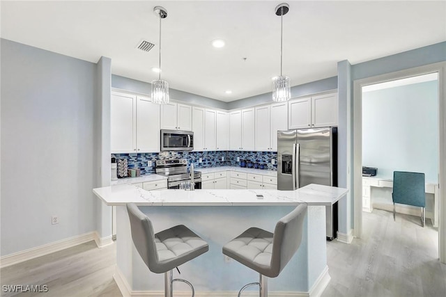 kitchen featuring white cabinets, pendant lighting, light stone counters, and stainless steel appliances