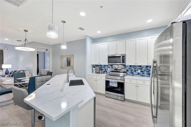 kitchen with white cabinetry, sink, hanging light fixtures, and appliances with stainless steel finishes