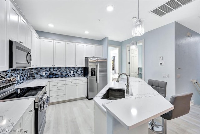 kitchen featuring a center island with sink, a breakfast bar, white cabinets, and appliances with stainless steel finishes