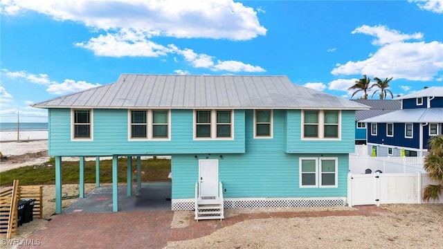 view of front of property with entry steps, decorative driveway, a water view, and a gate