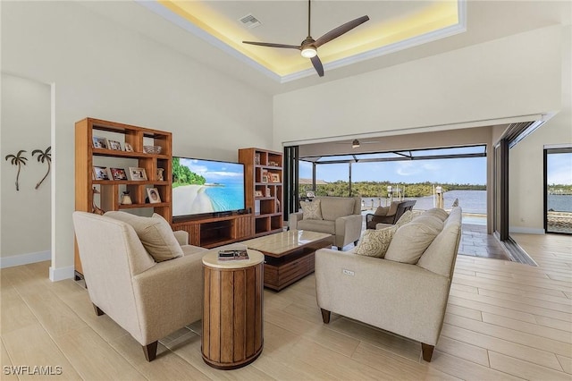 living room with ceiling fan and a raised ceiling