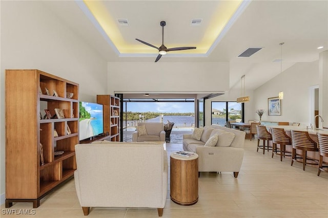 living room featuring ceiling fan, light hardwood / wood-style flooring, a raised ceiling, and sink