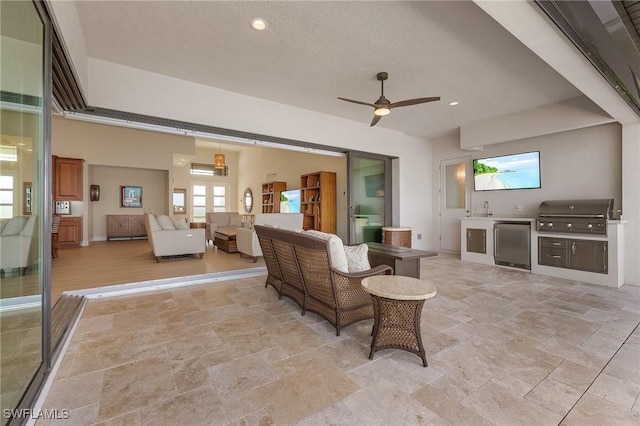 living room featuring ceiling fan, sink, and a textured ceiling