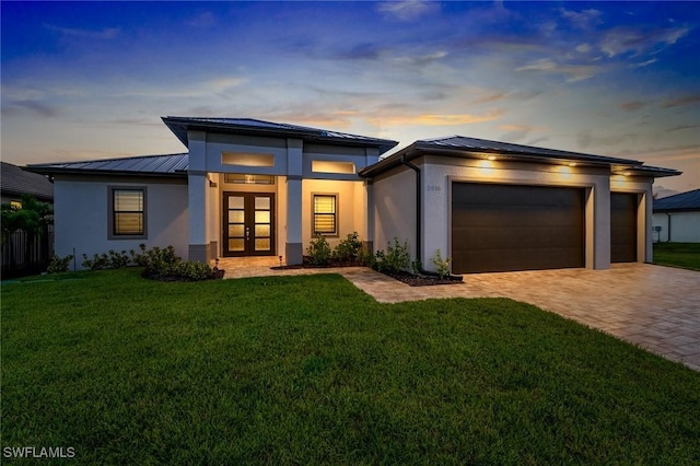 view of front of home with a garage, a yard, and french doors