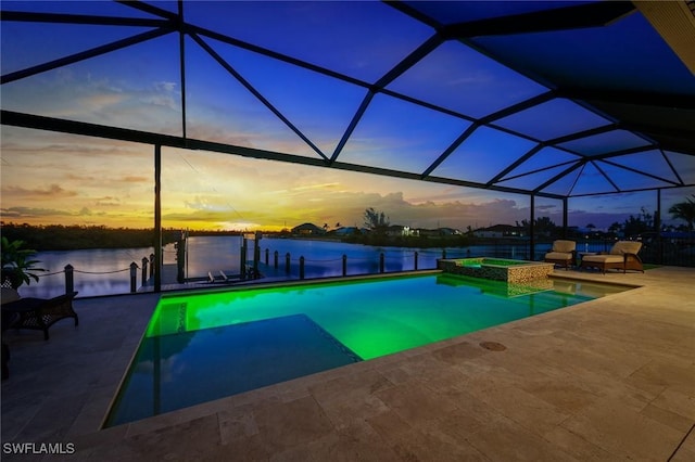 pool at dusk with a pool with connected hot tub, a water view, a patio area, glass enclosure, and a dock