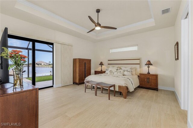 bedroom featuring ceiling fan, a water view, a raised ceiling, and access to outside