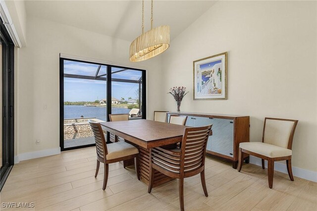 dining space with lofted ceiling, a water view, and light hardwood / wood-style flooring