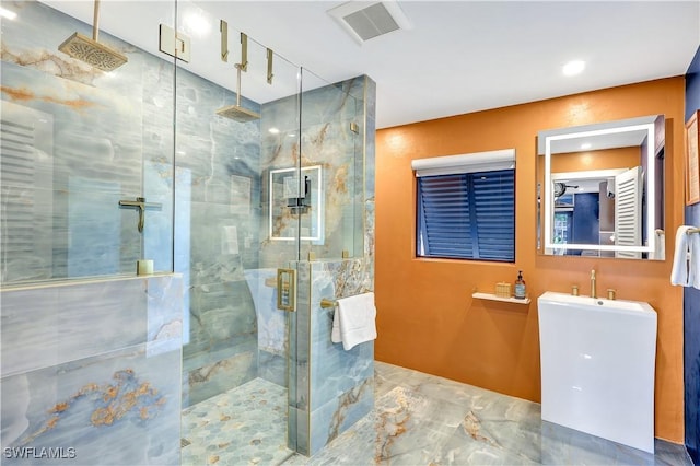 bathroom featuring a shower with door and sink