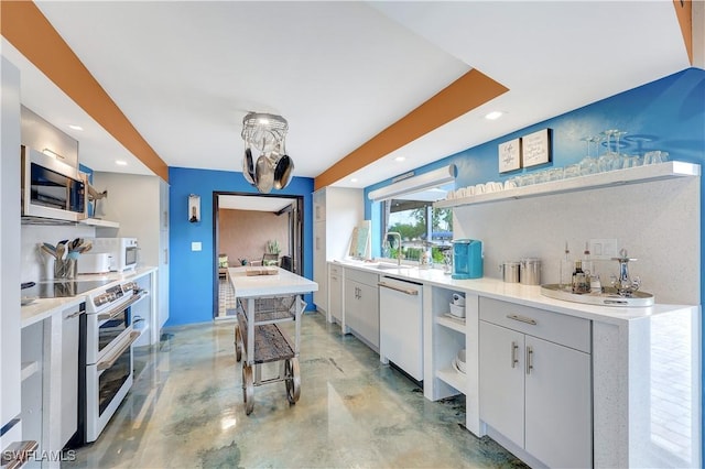 kitchen with white appliances, sink, tasteful backsplash, white cabinetry, and a breakfast bar area