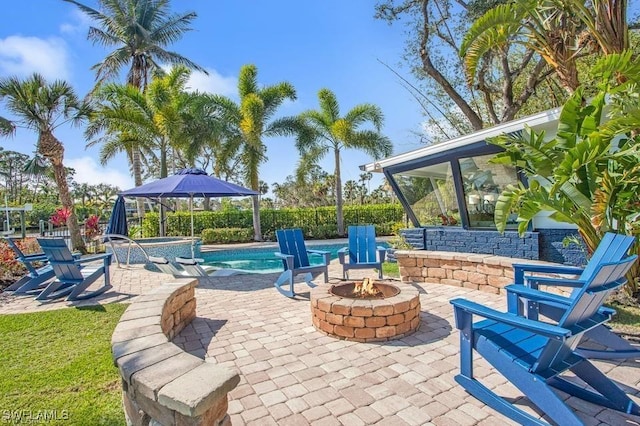 view of patio featuring a swimming pool with hot tub and an outdoor fire pit