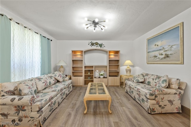 living room with light wood-type flooring, a textured ceiling, and a chandelier