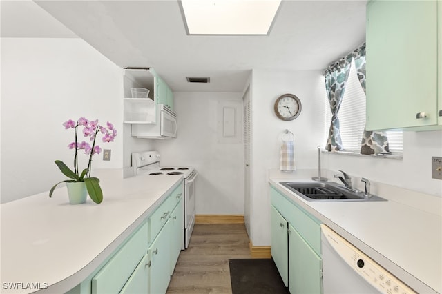 kitchen with green cabinetry, sink, white appliances, and light hardwood / wood-style flooring