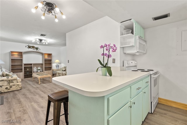 kitchen with kitchen peninsula, white appliances, a breakfast bar area, light hardwood / wood-style floors, and green cabinets