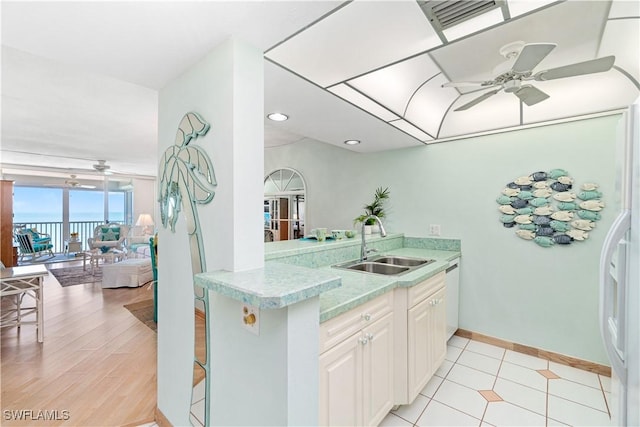 kitchen with kitchen peninsula, a kitchen bar, white cabinetry, and sink