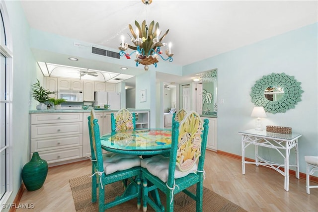 dining area with ceiling fan with notable chandelier and light wood-type flooring