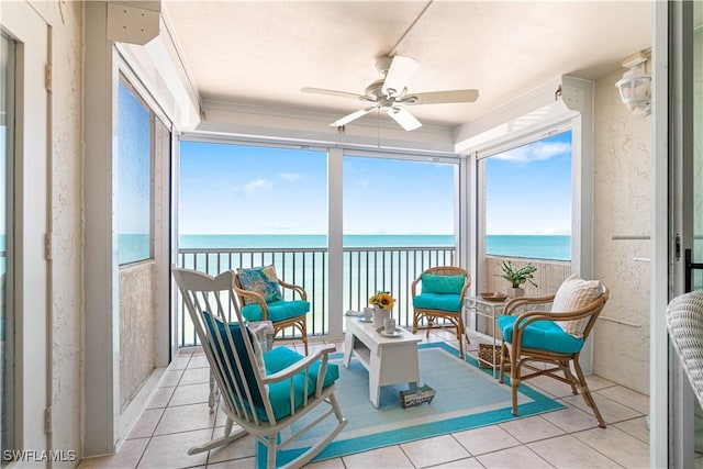 sunroom featuring ceiling fan and a water view