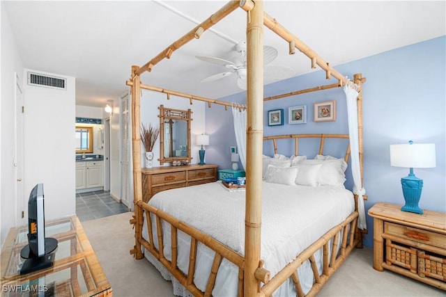 bedroom with connected bathroom, ceiling fan, and light carpet