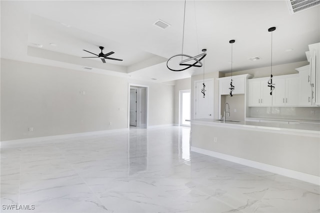 kitchen featuring white cabinets, decorative light fixtures, a tray ceiling, and ceiling fan