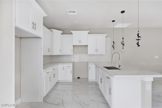 kitchen with white cabinets, decorative light fixtures, a kitchen island, and sink