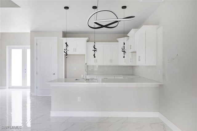 kitchen with kitchen peninsula, pendant lighting, white cabinetry, and sink