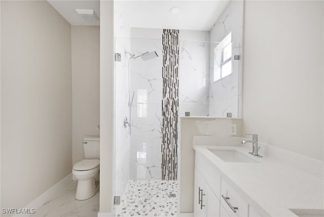 bathroom featuring a tile shower, vanity, and toilet