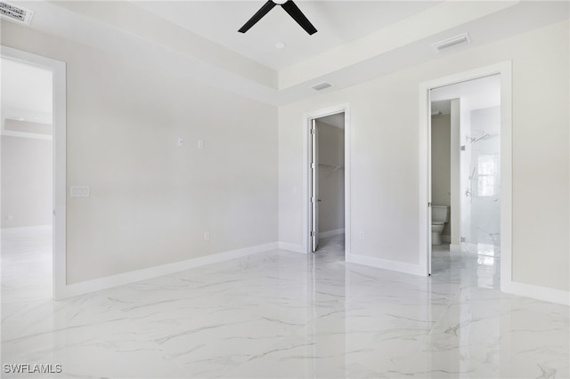 unfurnished bedroom featuring a walk in closet, a closet, ensuite bath, and ceiling fan