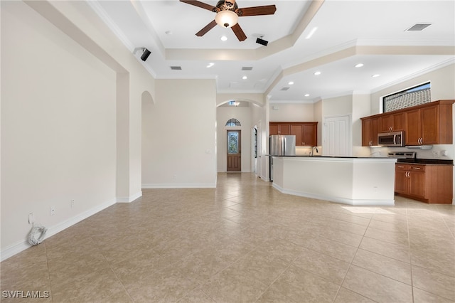 unfurnished living room with ornamental molding, a tray ceiling, ceiling fan, sink, and light tile patterned floors