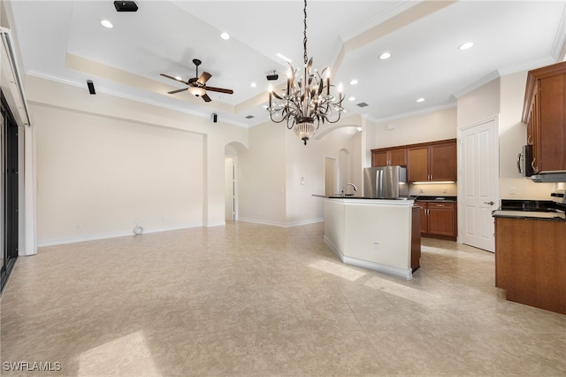 kitchen featuring decorative light fixtures, a kitchen island with sink, appliances with stainless steel finishes, and a tray ceiling