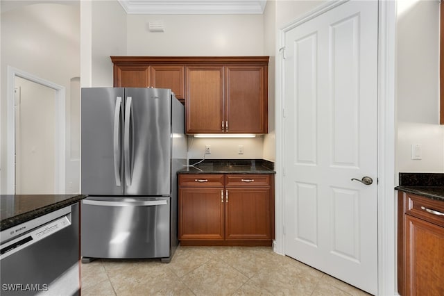 kitchen featuring dark stone countertops, light tile patterned floors, stainless steel appliances, and ornamental molding