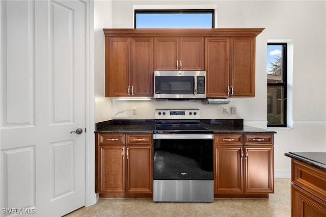 kitchen with light tile patterned floors, stainless steel appliances, a wealth of natural light, and dark stone countertops