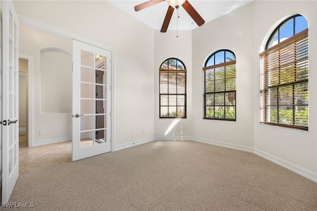 unfurnished room featuring ceiling fan, french doors, and light colored carpet