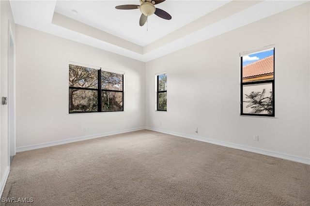 unfurnished room with a tray ceiling, ceiling fan, and carpet flooring