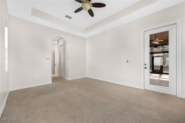 unfurnished room featuring ceiling fan, light colored carpet, and a tray ceiling