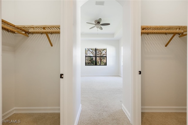 walk in closet with light carpet and ceiling fan