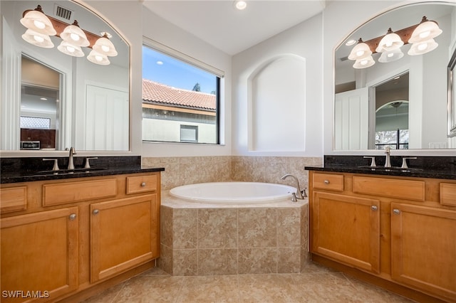 bathroom featuring vanity, tile patterned floors, and tiled tub