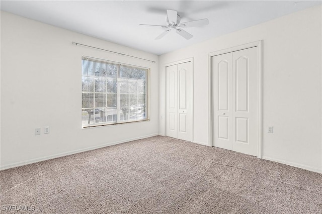 unfurnished bedroom featuring carpet flooring, multiple closets, and ceiling fan