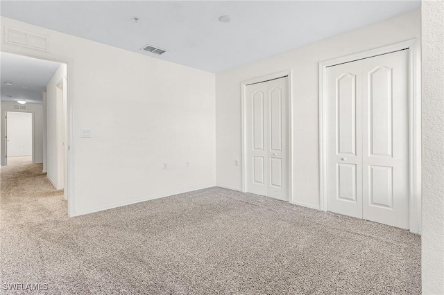 unfurnished bedroom with carpet flooring and two closets