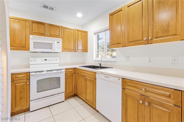 kitchen featuring sink, light tile patterned floors, and white appliances